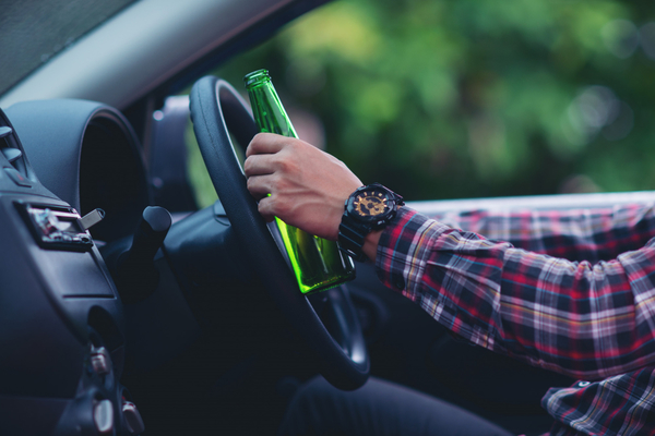 Asian-man-holds-a-beer-bottle-while-is-driving-a-car