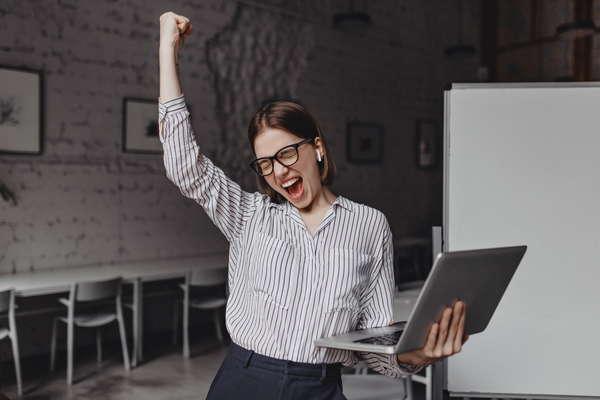 Woman-laptop-happy-success-glasses-striped-blouse-enthusiastically-screaming-and-making-winning-gesture