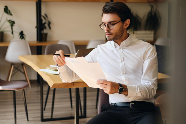 Businessman-eyeglasses-thoughtfully-working-with-papers-in-modern-office